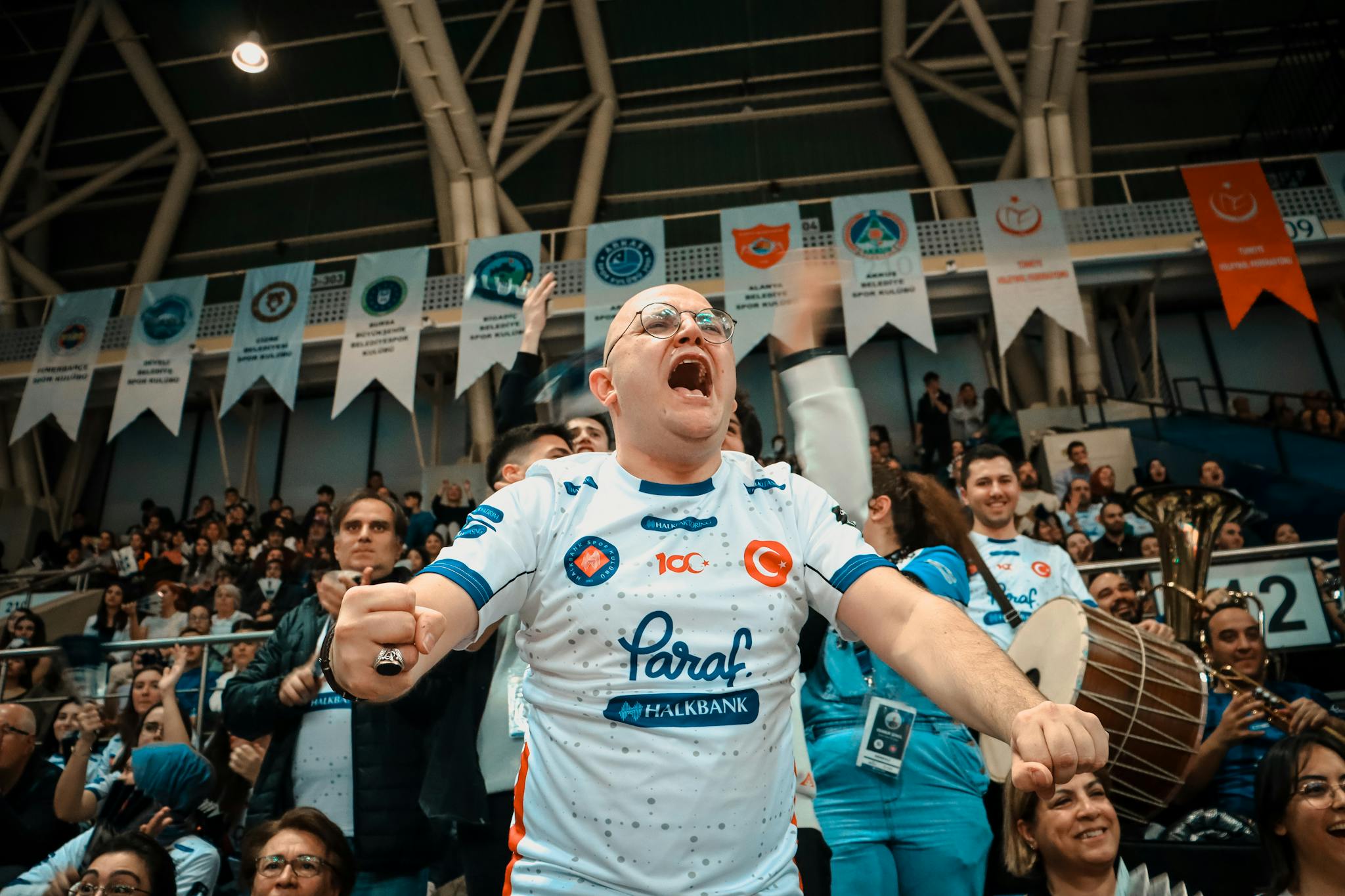 Passionate sports supporter in a crowded indoor arena, cheering with excitement.